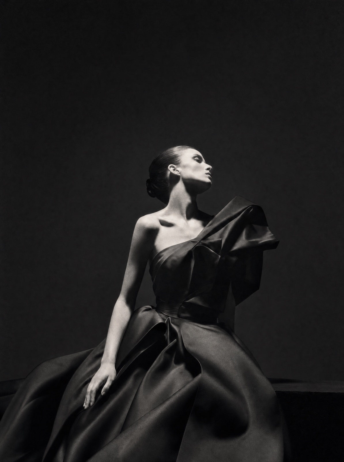 Black-and-white couture editorial still of a model in sculptural black silk.